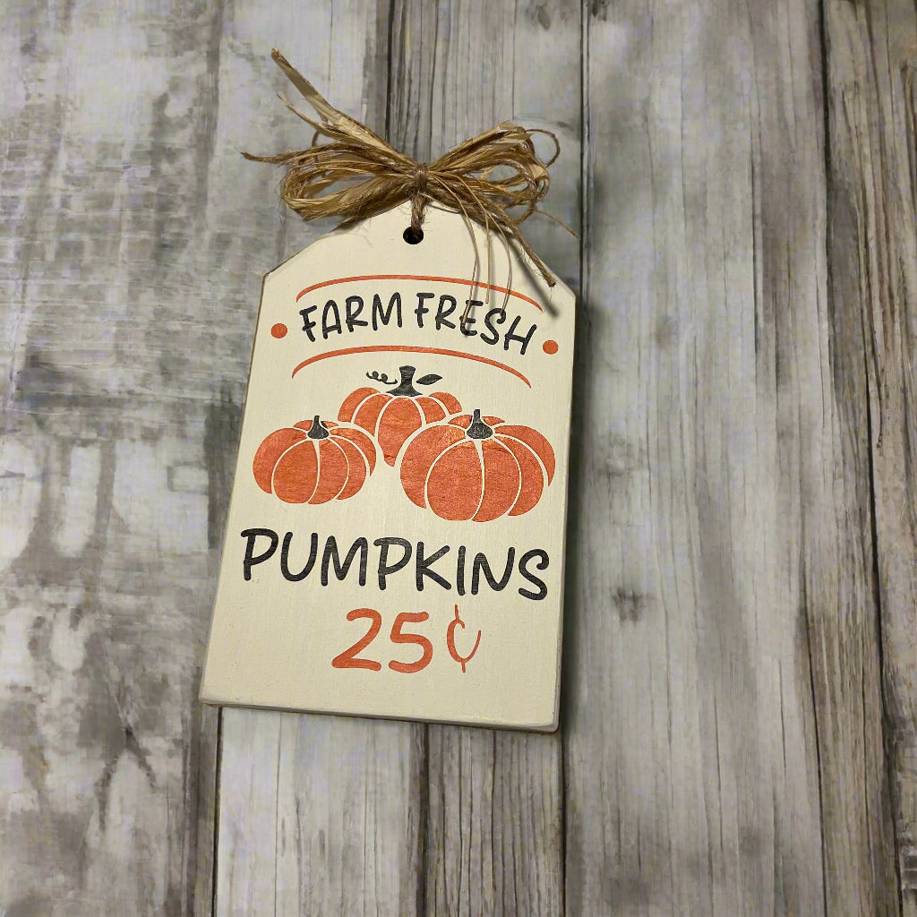 Decorative tag with 'Farm Fresh Pumpkins' text and pumpkin illustrations on a wooden background